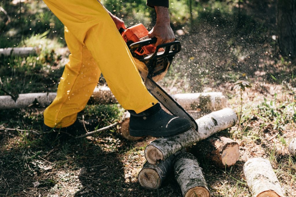 a man wearing personal protective gear chainsaw chaps while cutting a tree