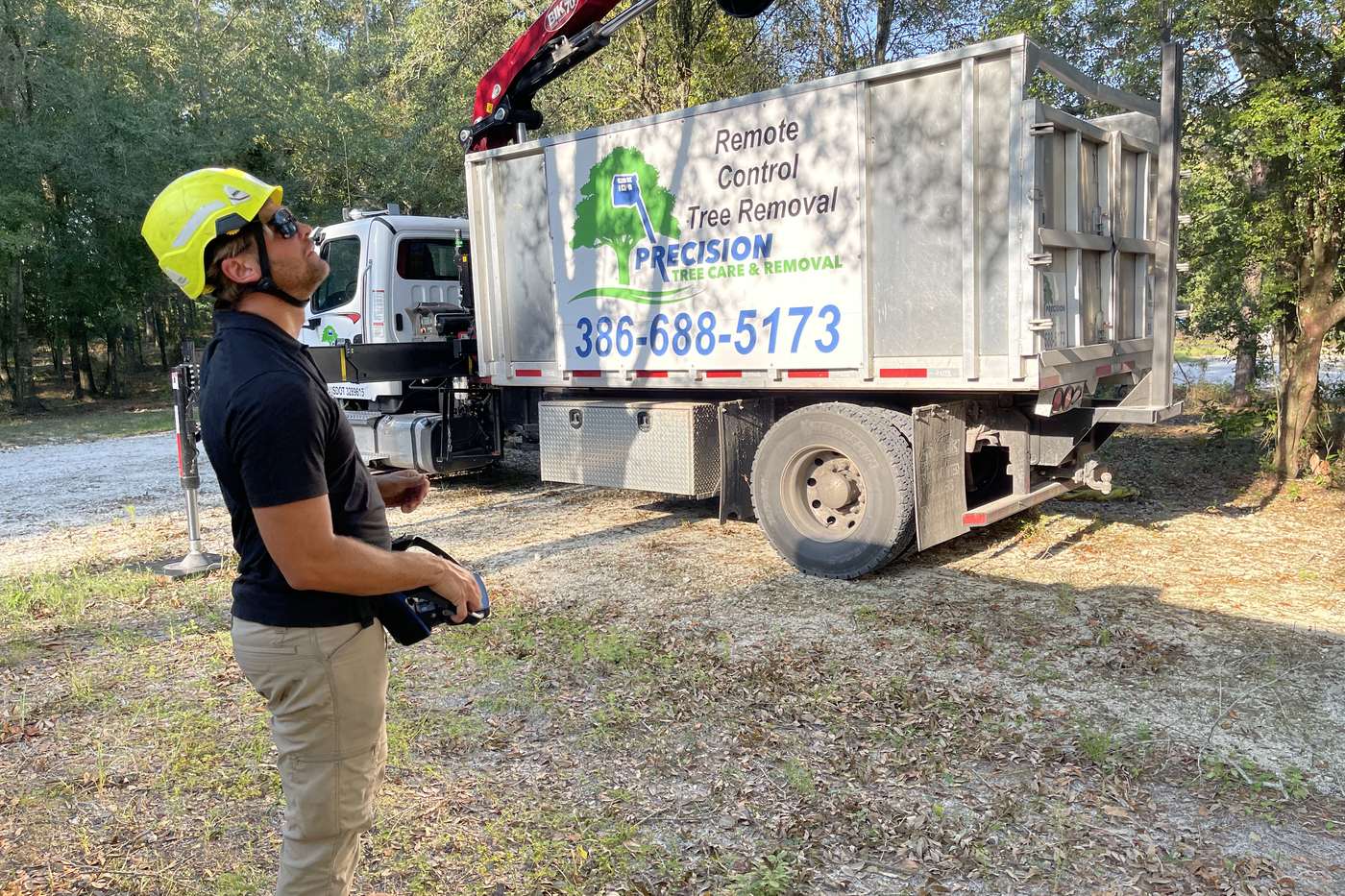 Precision Tree Care crew member running the remote-controlled grapple saw truck from the ground